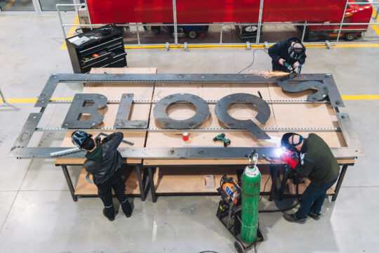 Bloqs' maker members finishing the sign for the new open access factory at Meridian Water. Photo: Claudia Agati. 